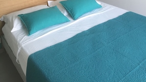 A bed with a wooden headboard, two teal pillows, and a teal blanket. - EXCEPTIONAL VIEW PINARELLO BAY AND NEEDLES BAVELLA Private Pool (Zonza)