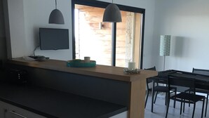 A modern kitchen with a central island, a dining area with a table and chairs, and a large window providing natural light. - EXCEPTIONAL VIEW PINARELLO BAY AND NEEDLES BAVELLA Private Pool (Zonza)