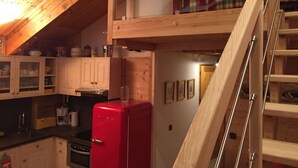 A kitchen with wooden cabinets, a red refrigerator, and a wooden staircase. - APARTMENT MANIGOD - The ÉTALE (La Clusaz) to SKI FOOT (MANIGOD)