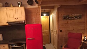 A compact kitchen with a red refrigerator, wooden cabinets, and a dining area with a table and chairs. - APARTMENT MANIGOD - The ÉTALE (La Clusaz) to SKI FOOT (MANIGOD)