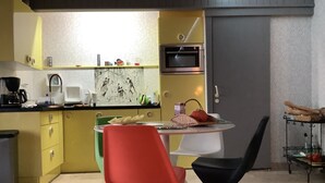 Een moderne keuken met gele kastjes, een magnetron en een eethoek met een opvallend stoelontwerp.