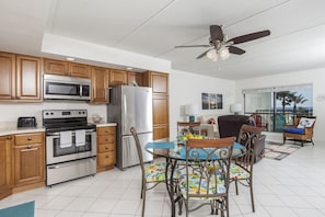 Enjoy meals in the kitchen with a central island and dining area featuring a glass-top table and outdoor views.