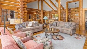 L’intérieur d’une cabane en rondins, avec deux canapés, une table basse et un tapis à motifs.