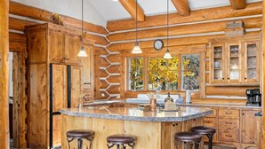 Une cuisine spacieuse avec un grand îlot central, des meubles en bois et des tabourets de bar.