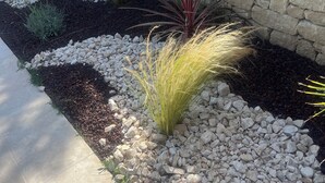 A stone wall with a garden bed containing various plants and rocks. - Family home, large pool – 15 min to Avignon (Villeneuve-Lès-Avignon)