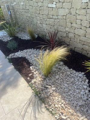 Eine steine Mauer mit einem Gartenbeet, das verschiedene Pflanzen und Steine enthält.
