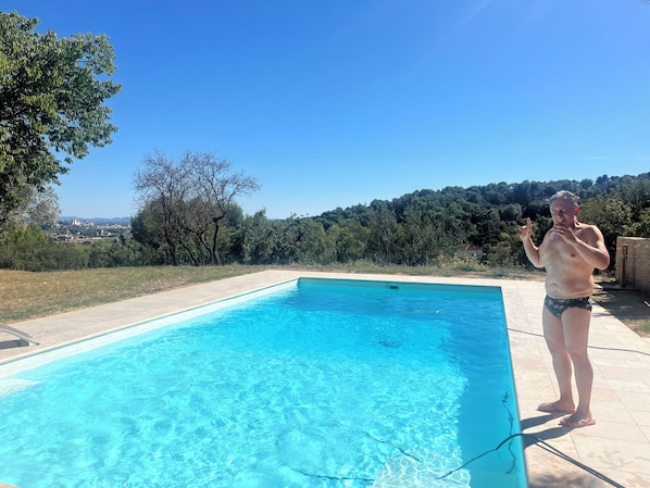 Ein Swimmingpool mit klarem, blauem Wasser, umgeben von einem Garten und Bäumen.