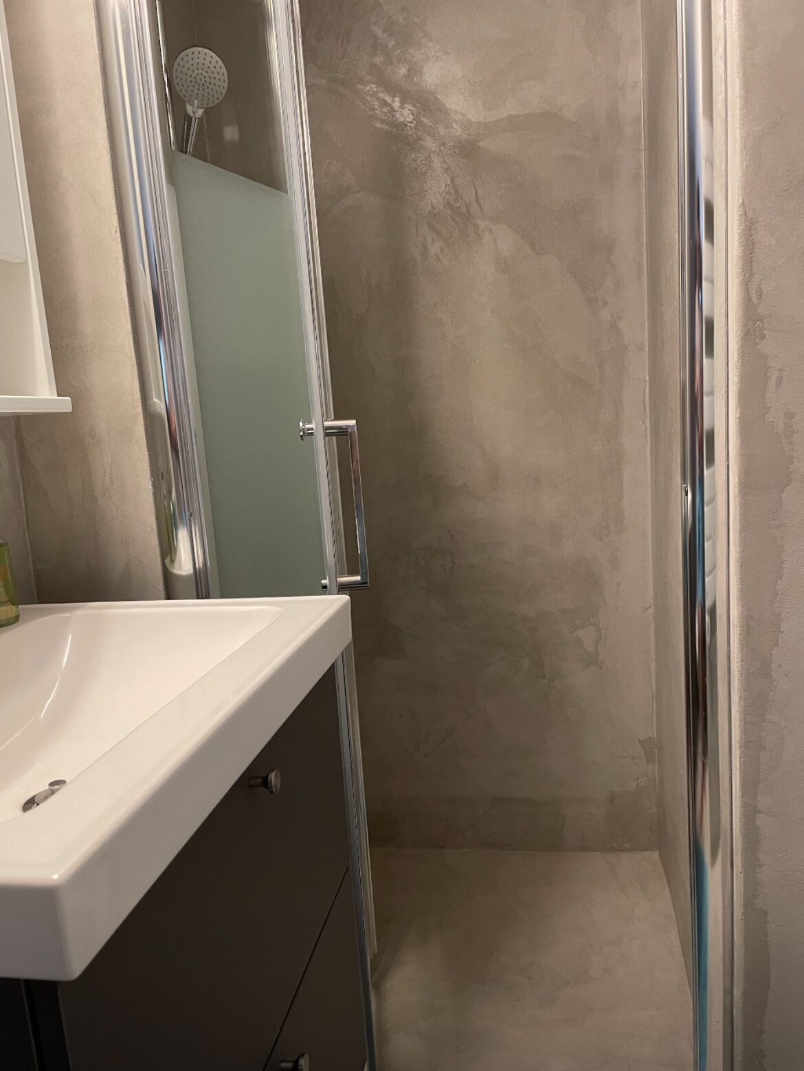 Ein Badezimmer mit Dusche, Waschbecken und Spiegel.