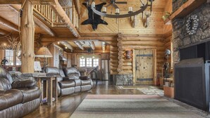 A log cabin interior with a fireplace, leather sofas, a chandelier, and antlers on the ceiling. - Stone Lodge-Panoramic Views, Lots of Space! (Lead)