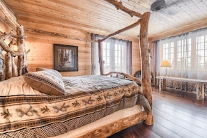 A rustic wooden room with a bed, a bench, and a framed picture on the wall. - Stone Lodge-Panoramic Views, Lots of Space! (Lead)