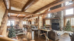 A log cabin interior with a fireplace, wooden furniture, and a Christmas tree. - Stone Lodge-Panoramic Views, Lots of Space! (Lead)