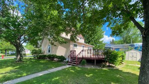 A house with a wooden deck, a small garden, and a pathway leading to the front door. - ALL OCCASION Central WI Home (Rothschild)