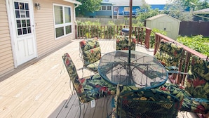 A wooden deck with a round table and chairs, a covered patio area, and a view of neighboring houses. - ALL OCCASION Central WI Home (Rothschild)