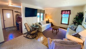 A living room with a television, a rocking chair, a sofa, and a dining area with a table and chairs. - ALL OCCASION Central WI Home (Rothschild)