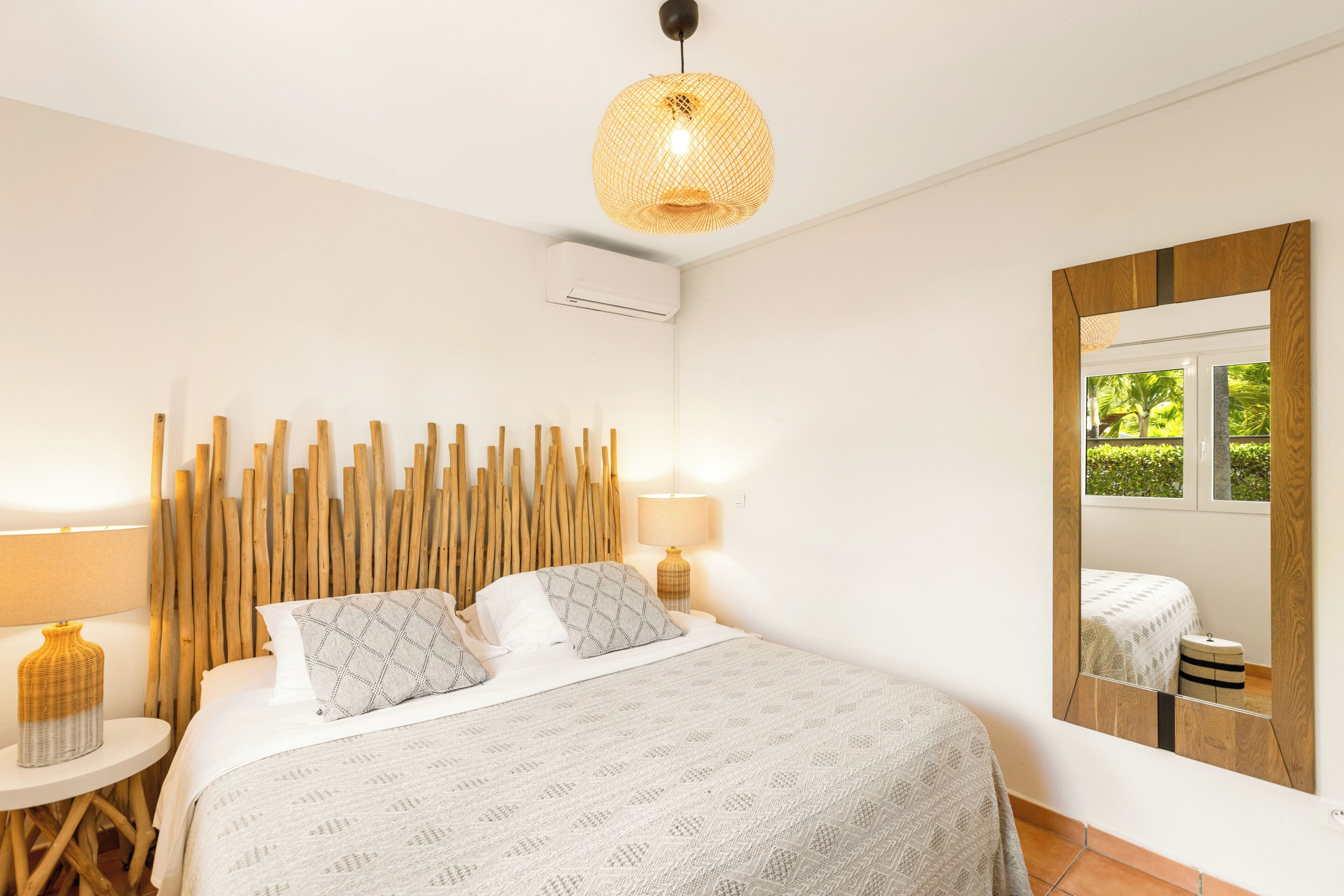 Une chambre à coucher avec un lit, des lampes de chevet, un miroir et un appareil de climatisation.