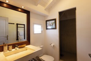 Un baño con lavamanos, inodoro y un cuadro en la pared.