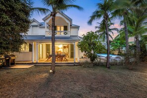 Une maison à deux étages avec un balcon, une terrasse dotée de mobilier d’extérieur et une piscine.