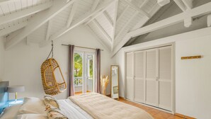 Un dormitorio con cama, una silla colgante, un armario y vistas al exterior.
