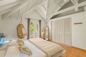 Une chambre à coucher avec un lit, un fauteuil suspendu, une armoire et une vue sur l’extérieur.