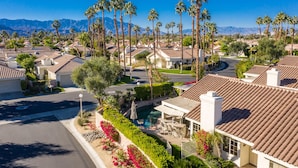 Zona residencial con casas, piscina y palmeras.
