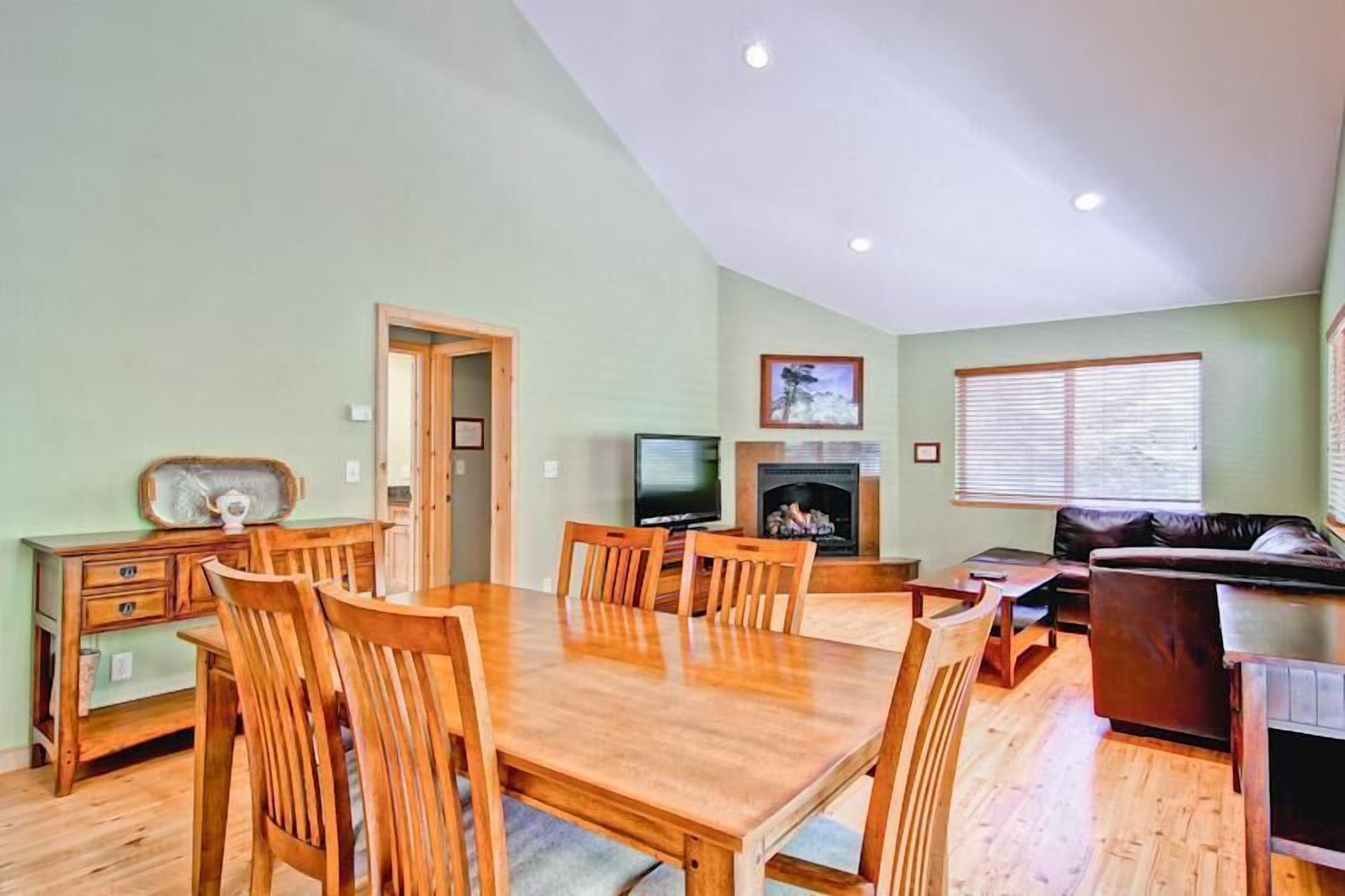 A dining area with a wooden table and chairs, a television, and a fireplace.