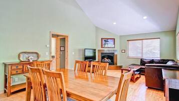 A dining area with a wooden table and chairs, a television, and a fireplace.