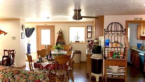 A spacious living area with a dining table, chairs, a sofa, and a kitchen area with cabinets and a refrigerator.
