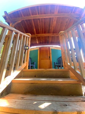 A wooden staircase leading to a covered area with a door at the top.