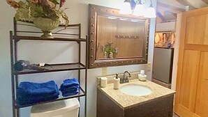 A bathroom with a vanity, sink, mirror, and a toilet.
