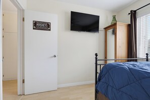 Une chambre avec un lit, un téléviseur fixé au mur, une porte ornée d’une enseigne Hershey’s et un meuble en bois.