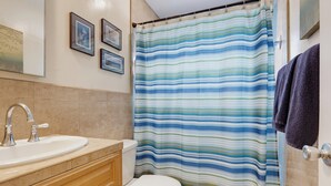 Une salle de bain avec un rideau de douche à rayures, un lavabo et des toilettes.