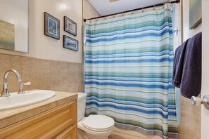 Een badkamer met een douchegordijn met strepen, een wastafel en een toilet.