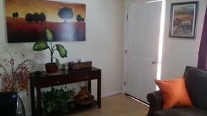 A living room with a dark wooden coffee table, a potted plant, a vase, and a framed picture on the wall.