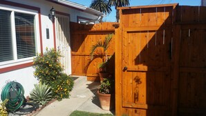 A wooden gate, a potted plant, and a small tree in a residential backyard.