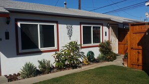 A single-story house with two windows, a small front yard, and a wooden fence.