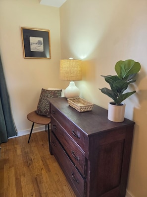 A wooden dresser with drawers, a lamp, a potted plant, and a framed picture on the wall. - Yellowstone Vacation Condo (Miles City)