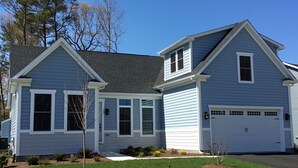 Une maison à deux étages avec un garage, un porche à l’avant et une pelouse bien entretenue.