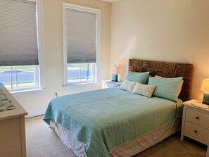 A bedroom with a bed, bedside tables, a lamp, and a window with blinds.