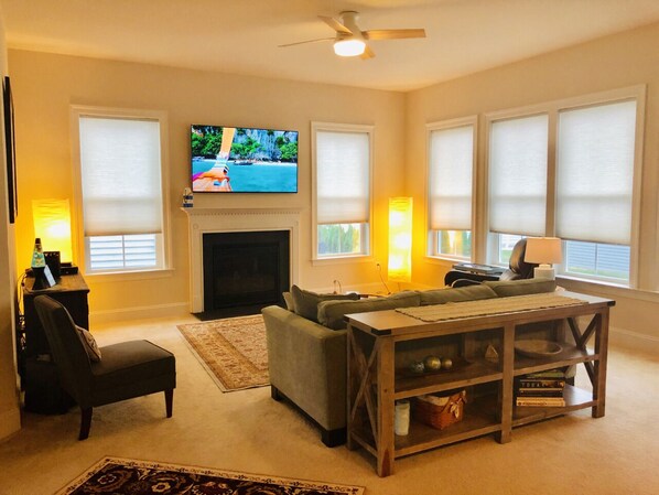 A living room with a fireplace, a television, a sofa, a coffee table, and a chair.
