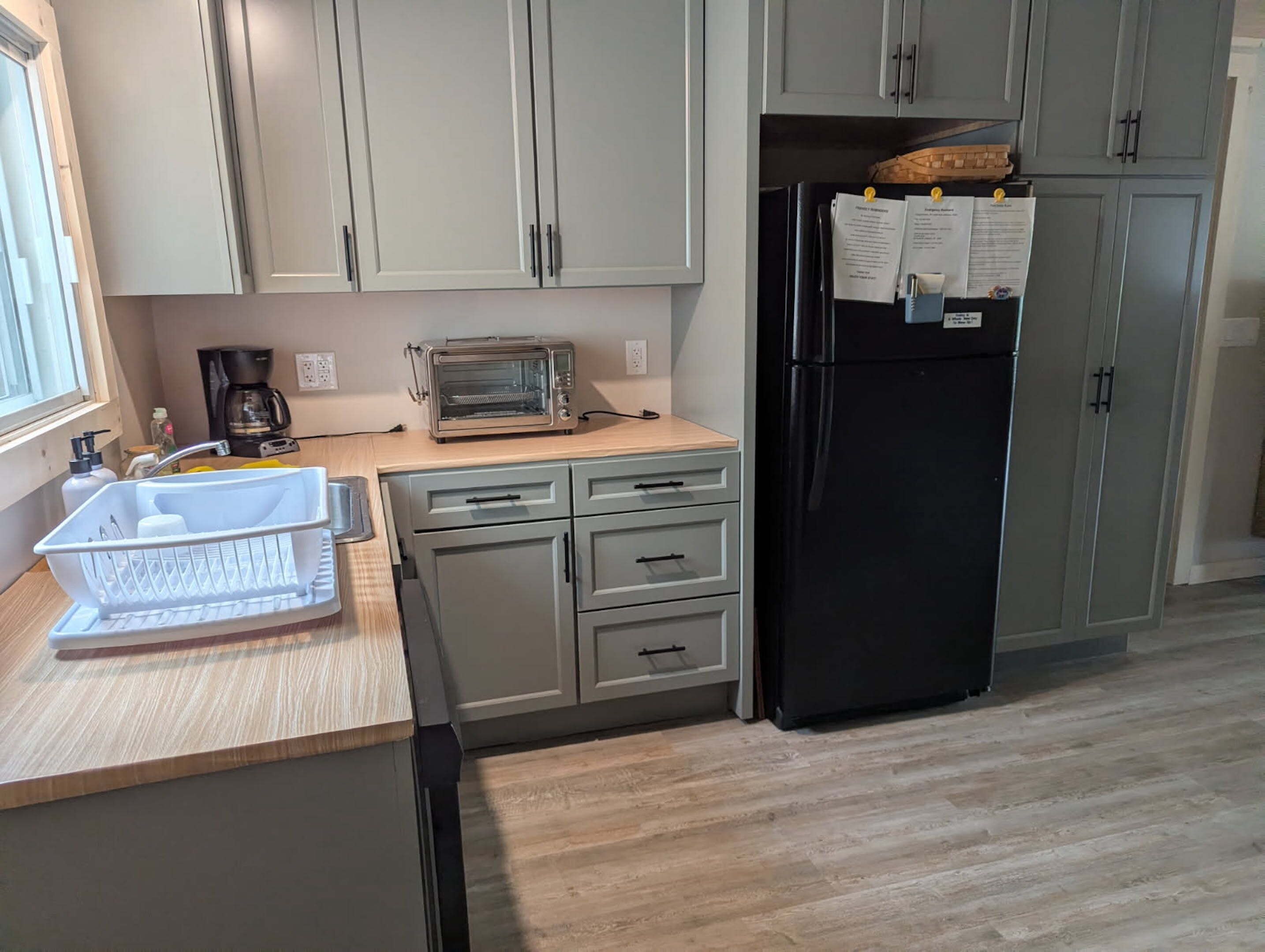A kitchen with a toaster, a refrigerator, and a sink.