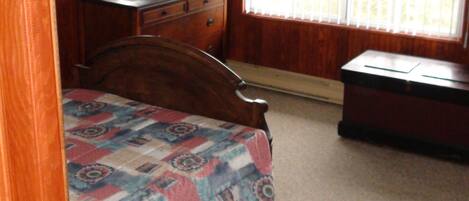Une chambre à coucher avec un lit, une commode et une fenêtre équipée de stores.