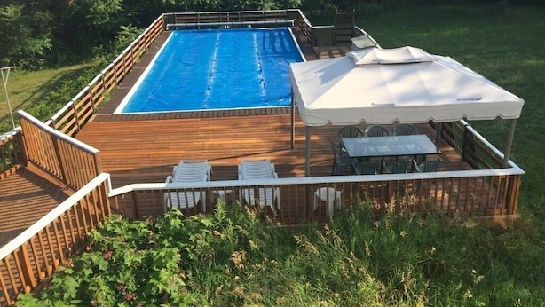 A rectangular pool with a wooden deck and a covered seating area with tables and chairs. - Caron Hideaway - Lakefront House - Private Pool and Beach (Willsboro)