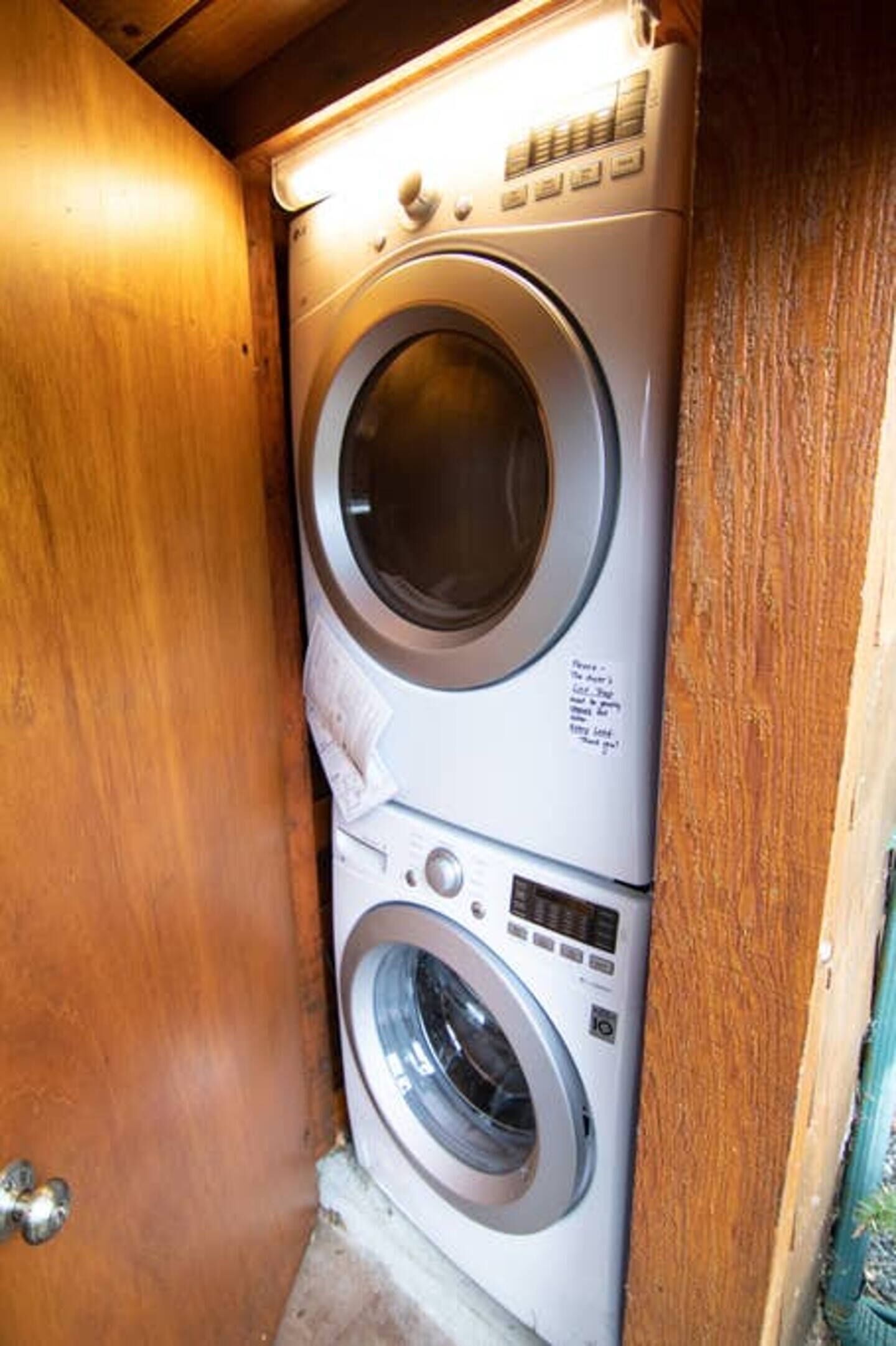 A compact, two-door laundry room with a wooden door and a built-in washer and dryer.