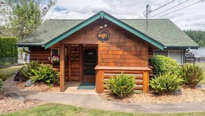 A log cabin with a green roof, a front porch, and a circular emblem above the door. - ~ Lakeside Log Cabin ~ Blessings & Memories Abound! (Graham)