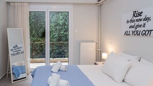 Hotelkamer met een groot bed, een spiegel, uitzicht op groen en een motiverende poster aan de muur.