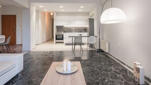Een moderne keuken met witte kastjes, een decoratieve achterwand en een eethoek met een tafel en stoelen.