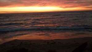Une plage avec des vagues et un coucher de soleil.