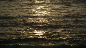 Un coucher de soleil sur l’océan, avec la lumière du soleil se reflétant sur l’eau.