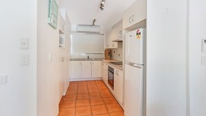 Una cocina compacta con armarios blancos, horno integrado y refrigerador.