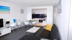Un salon moderne comprenant un canapé, une table basse, un téléviseur et un coin repas avec des chaises et une table.